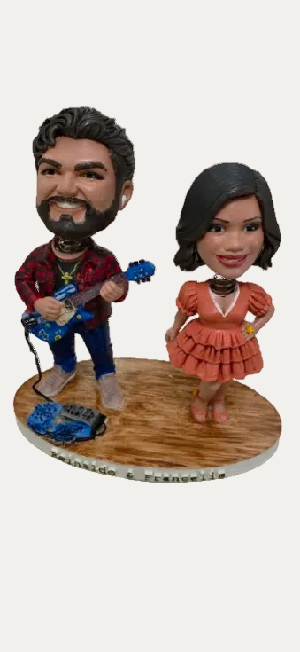Bobblehead figures of a man playing guitar and a woman in a dress on a wooden base.